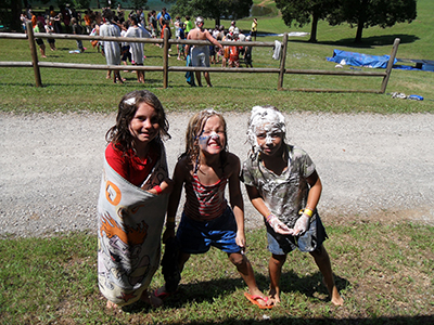 3 girls posing for a picture covered in mud and shaving cream